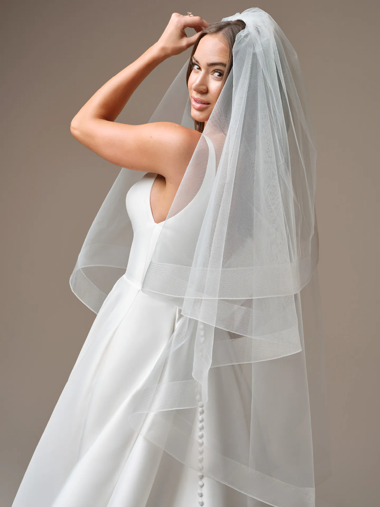 Maggie Sottero Galina A-Line wedding dress, side view with veil and buttons in focus.