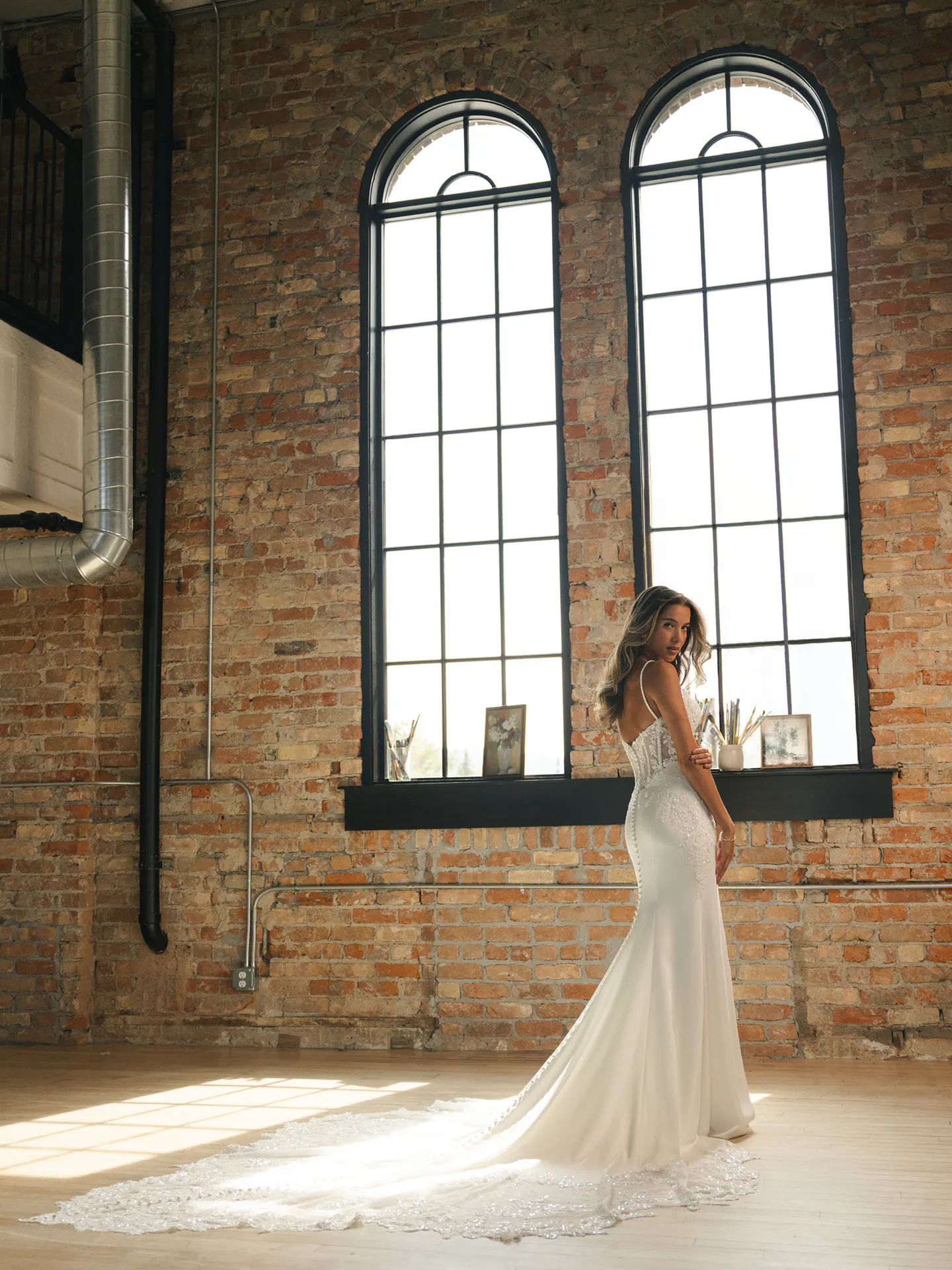 Maggie Sottero India, back view beaded sheath wedding dress in loft setting.