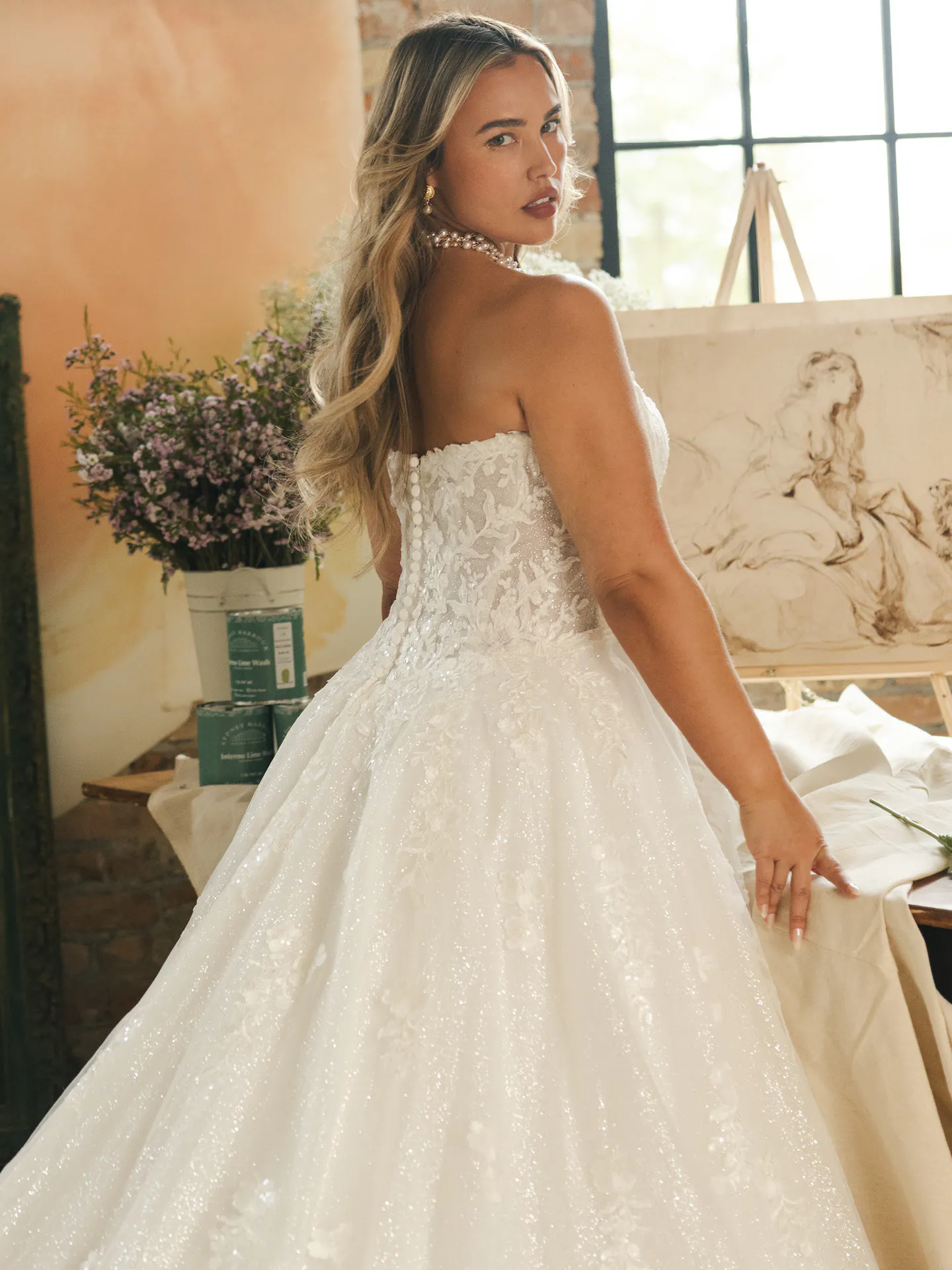 Maggie Sottero Jennifer, back view, sequin A-line dress in artistic setting.