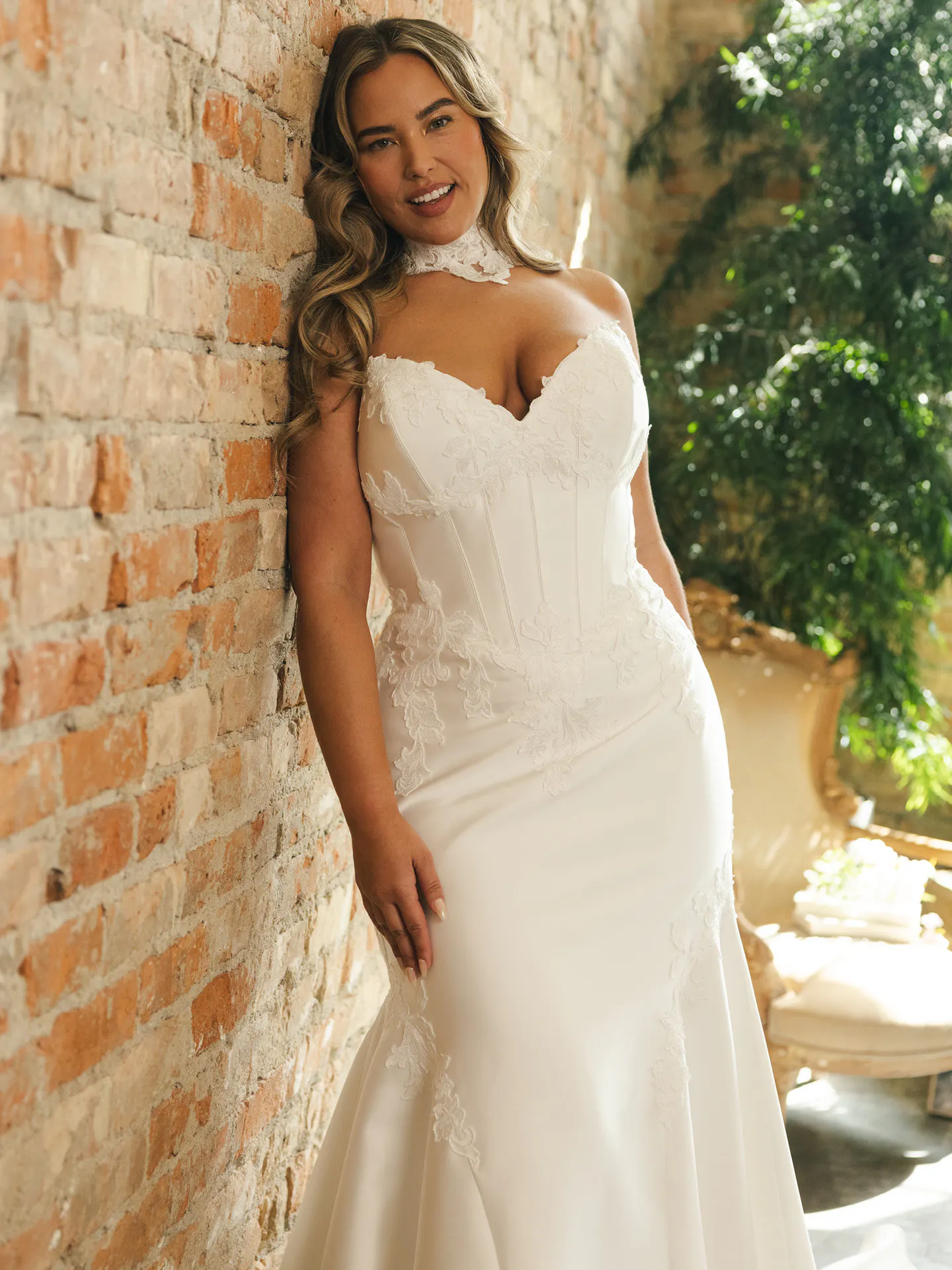 Serafina satin ball gown, front view, lace details, brick wall background.