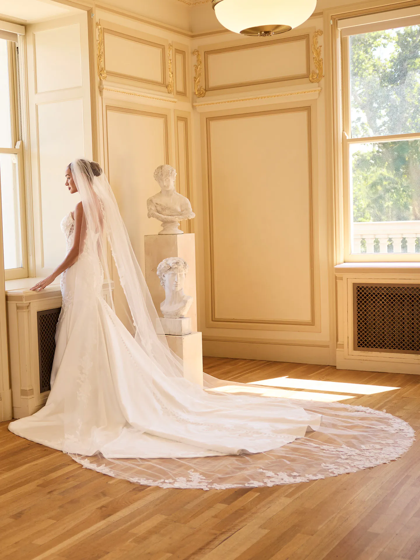 Maggie Sottero Burke, side view in elegant room with lace fit-and-flare and long train.
