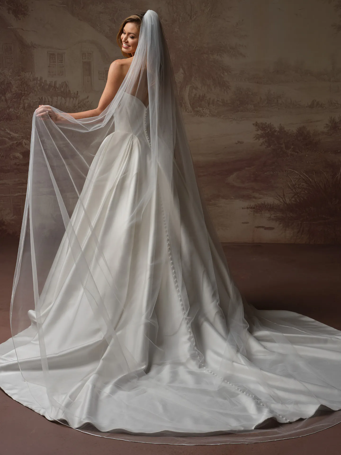 Maggie Sottero Fiorita back view; draped bodice, basque waist, chapel train, veil draped.